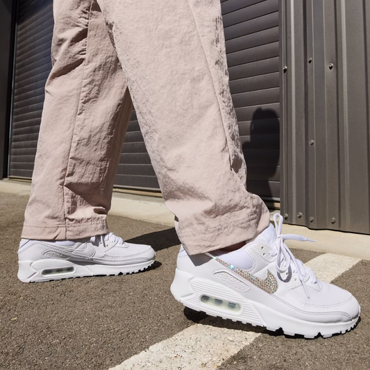 Person wearing light pink pants and white sneakers in front of a metallic shutter.